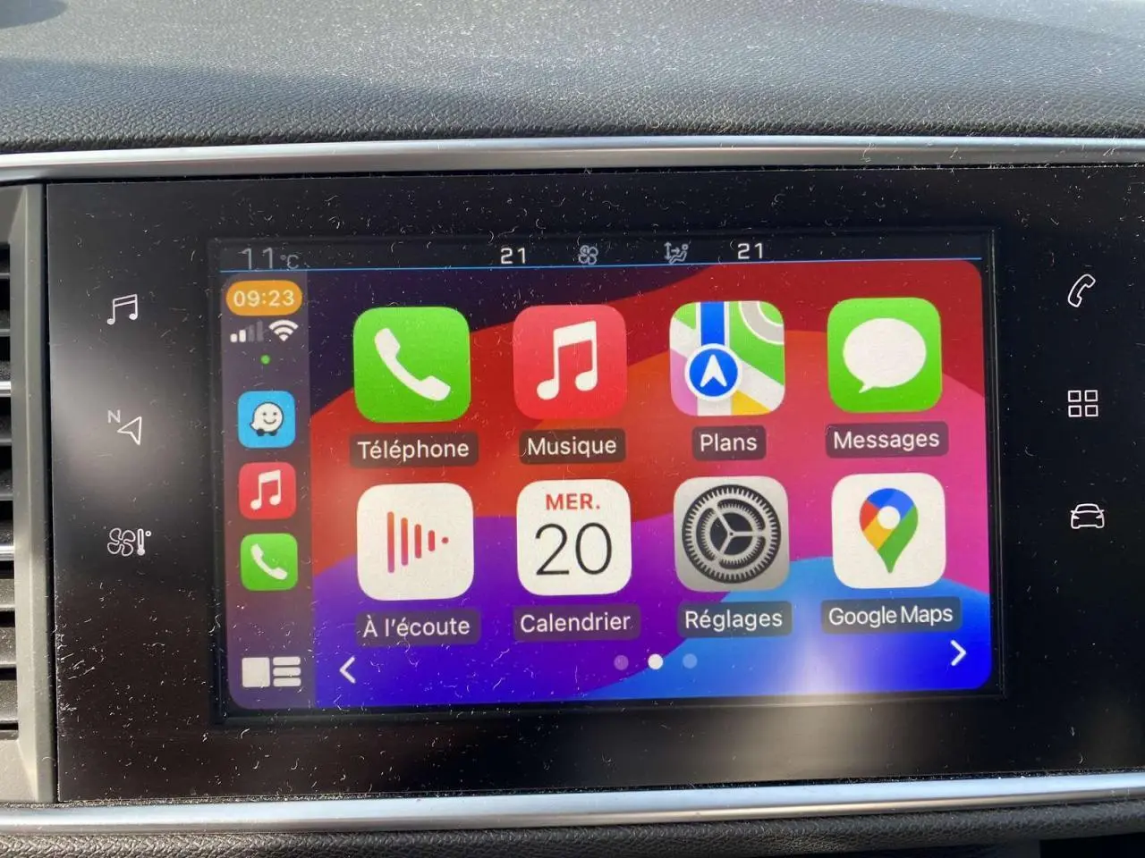 Écran tactile central de la Peugeot 308 blanc nacré, affichant l'interface Apple CarPlay avec applications colorées.