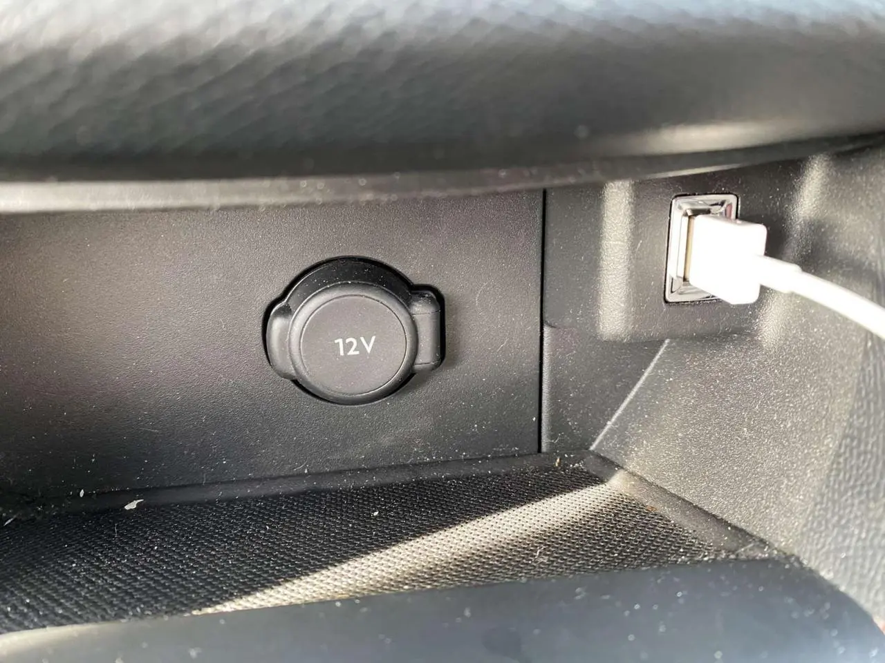 Prise 12V et port USB avec câble blanc dans l’habitacle noir de la Peugeot 308 blanche, version Allure.