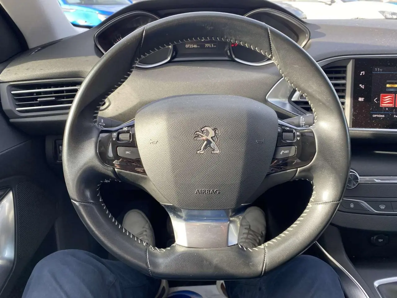 Vue centrée sur le volant cuir du Peugeot 308 blanc nacré 2017, avec tableau de bord et écran tactile visible à droite.