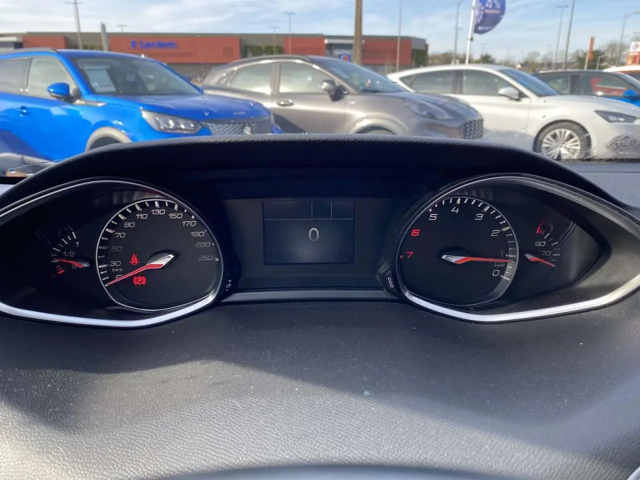 Vue rapprochée du tableau de bord de la Peugeot 308 blanche, affichant les compteurs à zéro en plein jour.