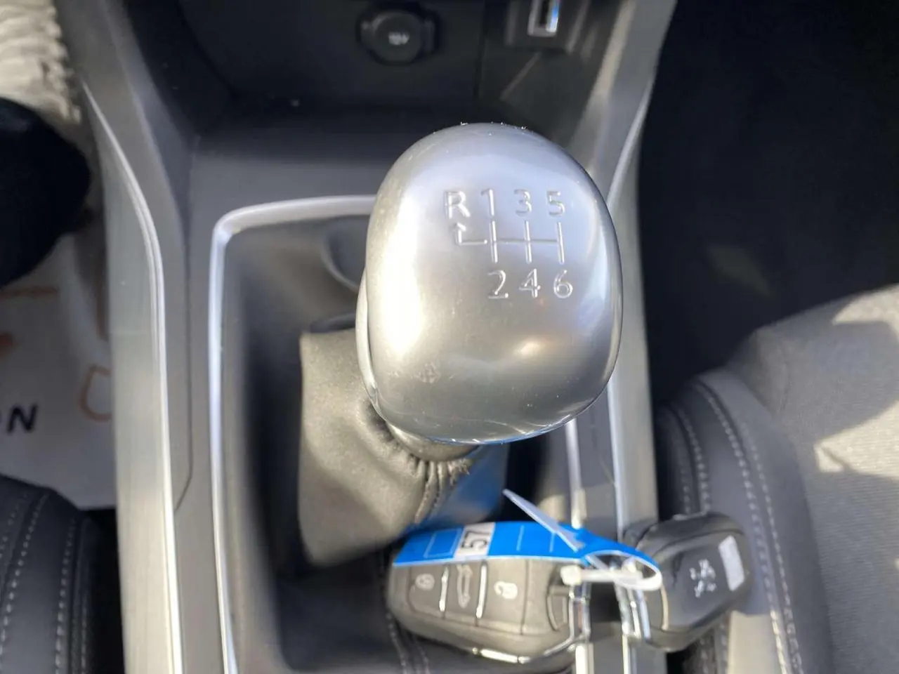 Le levier de vitesses manuel argenté de la Peugeot 308 blanche, vu en gros plan depuis l'intérieur.