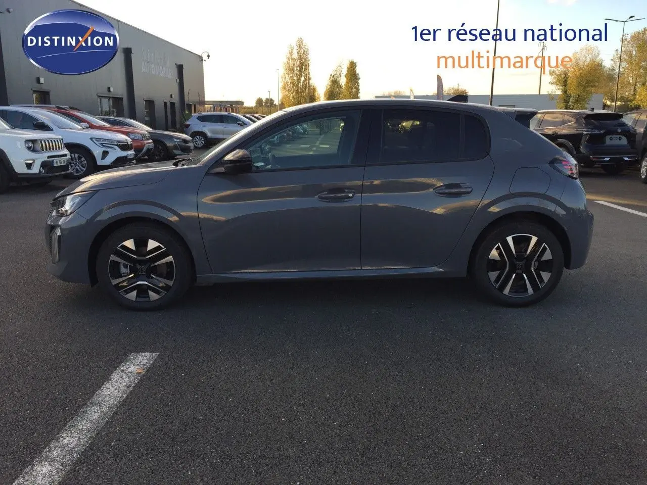 Profil côté gauche d'une Peugeot 208 hybride gris selenium métal garée sur un parking extérieur au coucher du soleil.