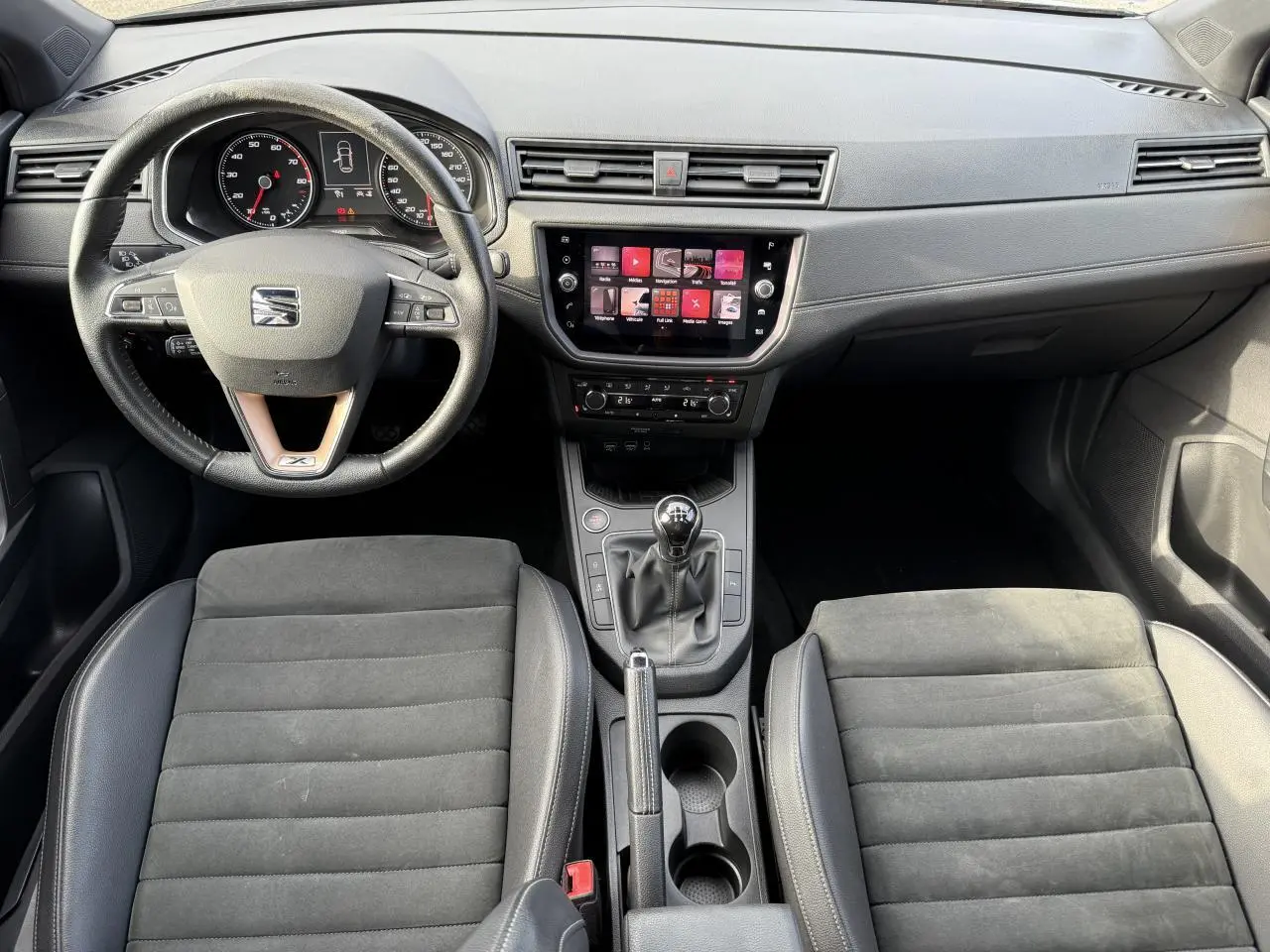 Intérieur de la SEAT Ibiza 2019 vu de face, tableau de bord noir avec écran tactile et boîte manuelle.