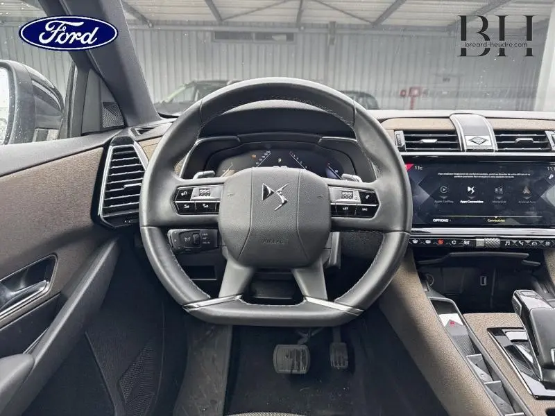 Vue intérieure centrée sur le volant cuir noir du DS7 Crossback gris Platinium avec tableau de bord numérique et écran tactile.