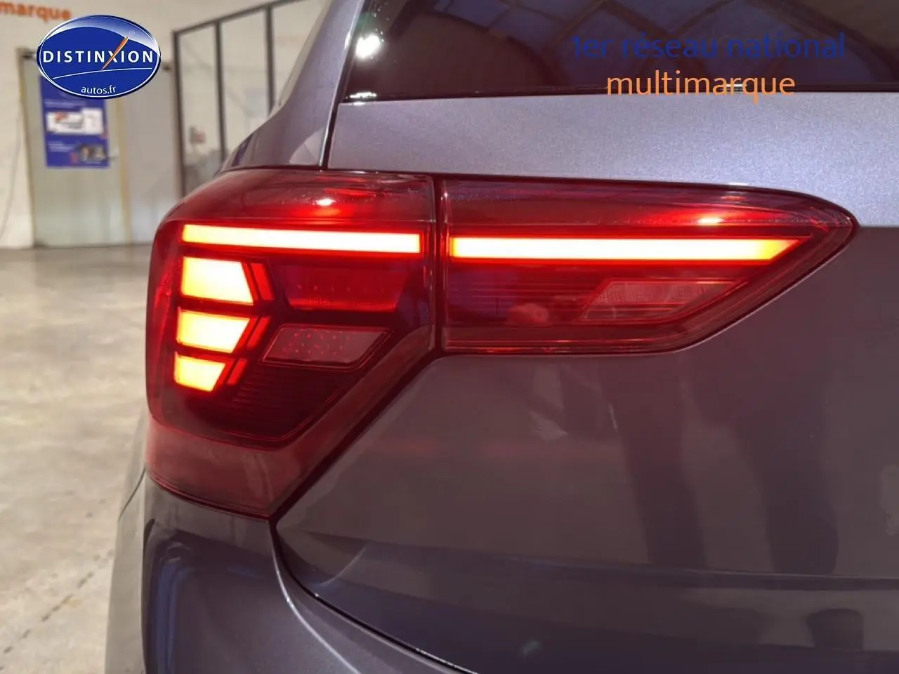 Gros plan sur le feu arrière droit allumé d'une Volkswagen Polo gris cendre dans un garage intérieur.