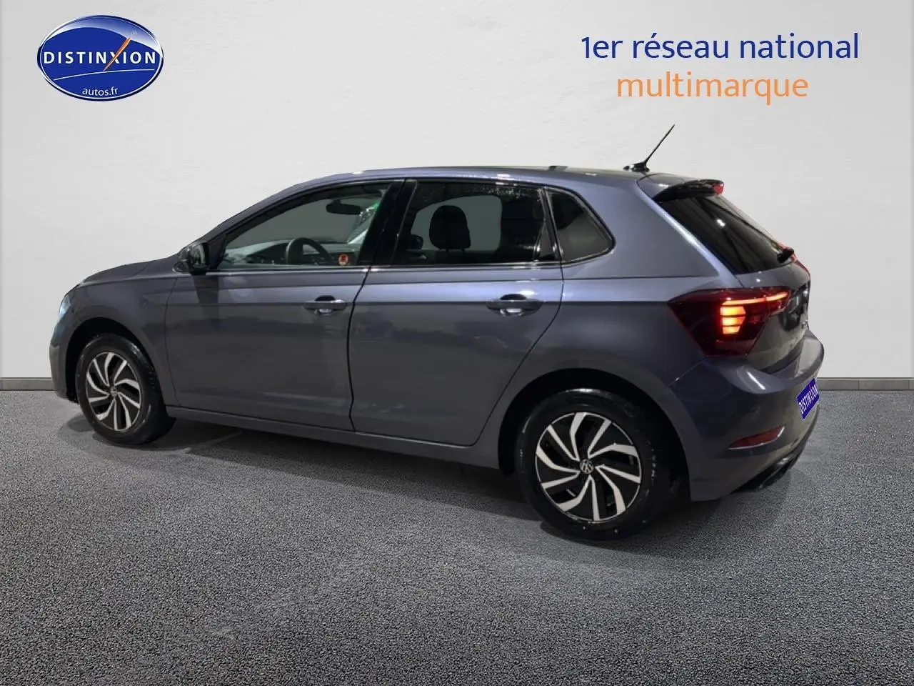 Volkswagen Polo gris cendre vue de profil côté gauche, feux arrière allumés et jantes alliage noires.