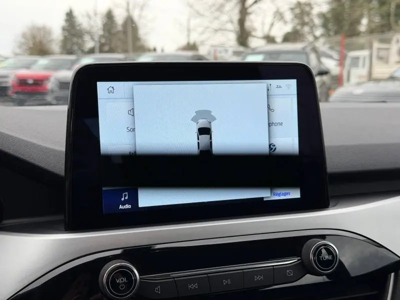 Écran central tactile du Ford Kuga 1.5 EcoBoost 150ch Titanium 2024 montrant l'assistance au stationnement, intérieur gris clair.