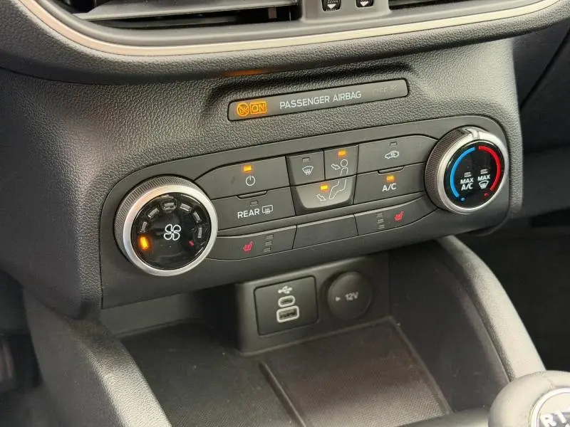 Gros plan sur la console centrale du Ford Kuga 2024, montrant les commandes de climatisation et les voyants allumés.