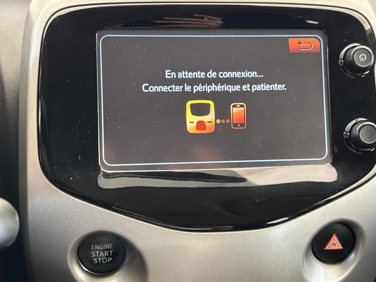 Écran tactile central affichant un message de connexion dans l’habitacle d’une Toyota Aygo gris clair.