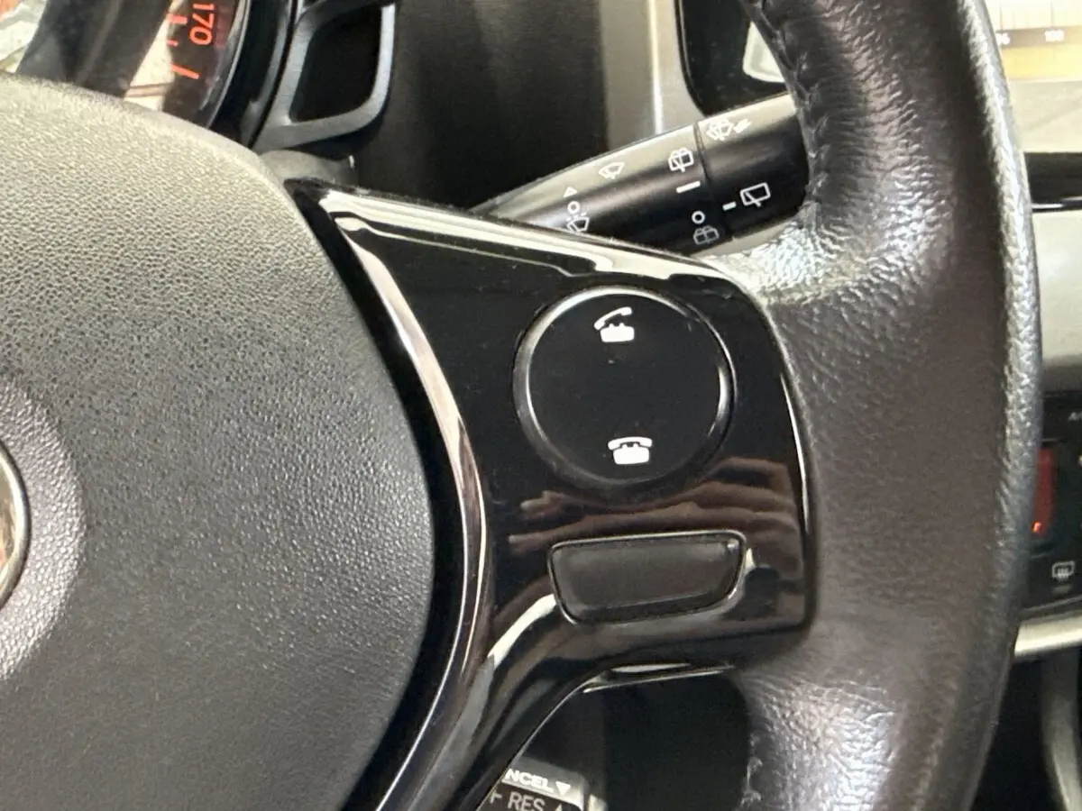 Gros plan sur le volant noir de la Toyota Aygo 2017, montrant les commandes d’appel téléphonique intégrées.