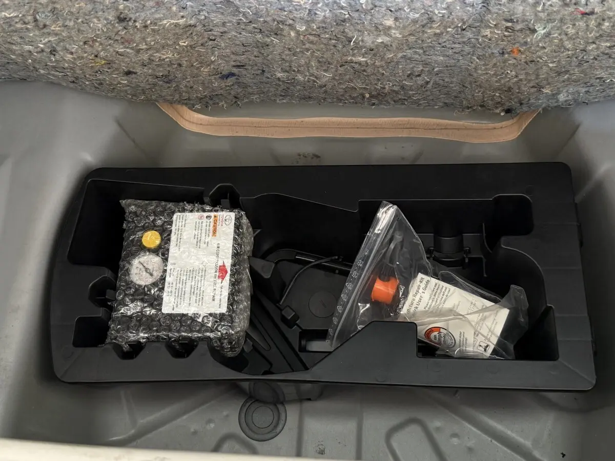 Vue plongeante sur le compartiment de rangement sous la moquette grise d'une Toyota Aygo gris clair de 2017.
