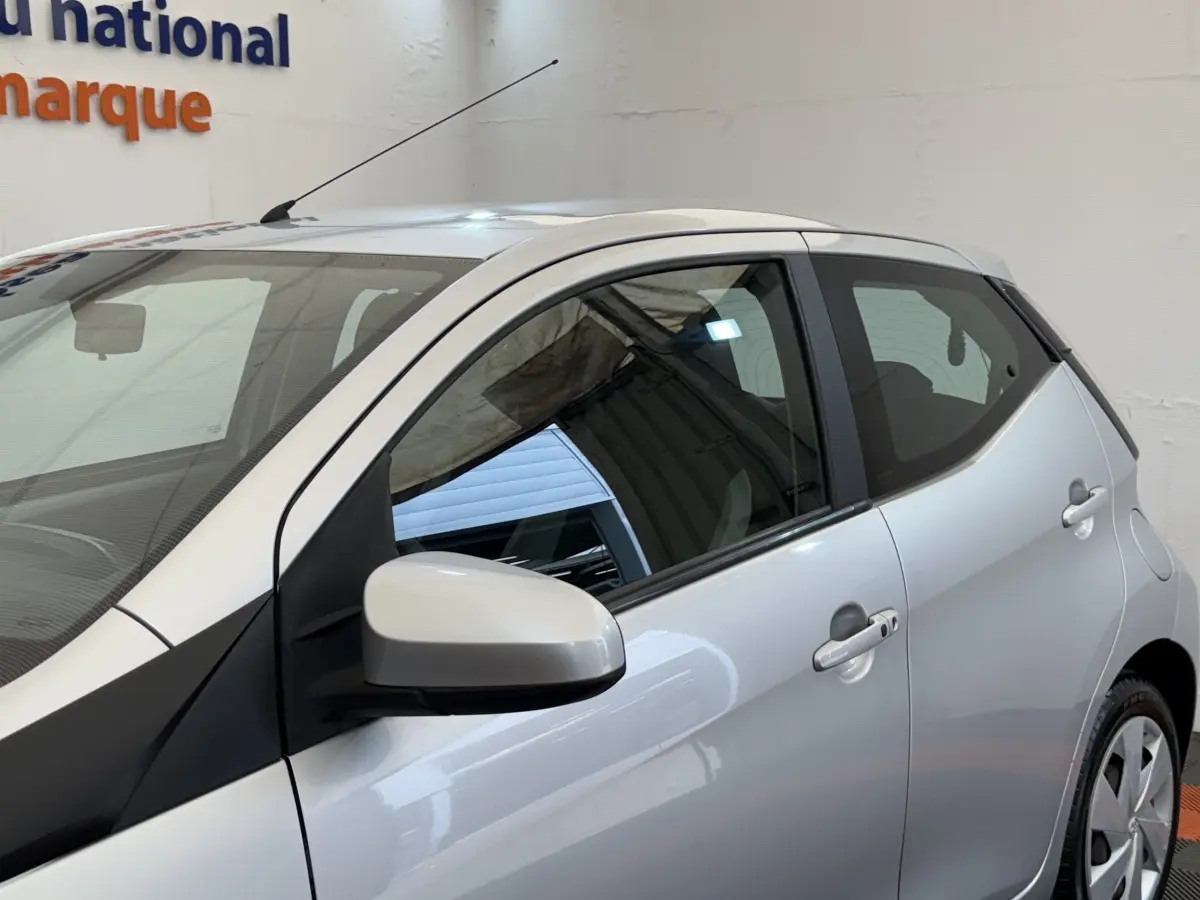 Vue latérale droite d'une Toyota Aygo gris clair 2017 avec rétroviseur assorti et poignées de porte visibles.
