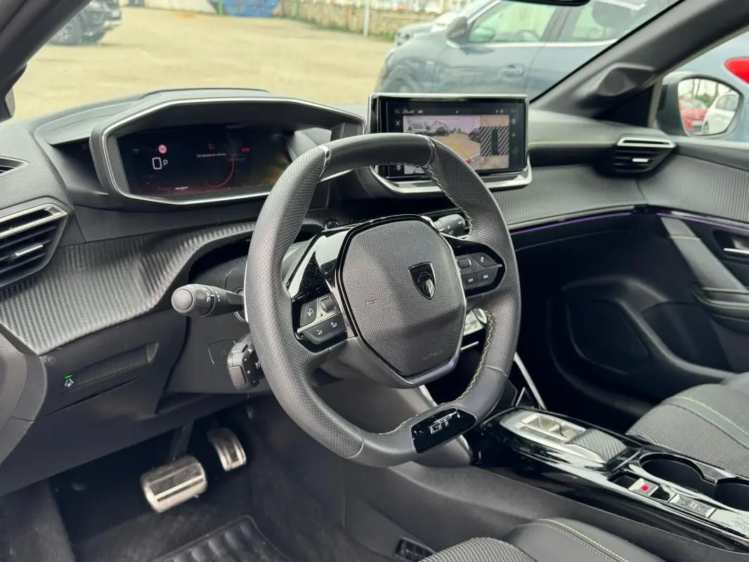 Vue intérieure du poste de conduite de la Peugeot 208 Hybrid 110 e-DCS6 GT 2025, volant GT et écran tactile visible.
