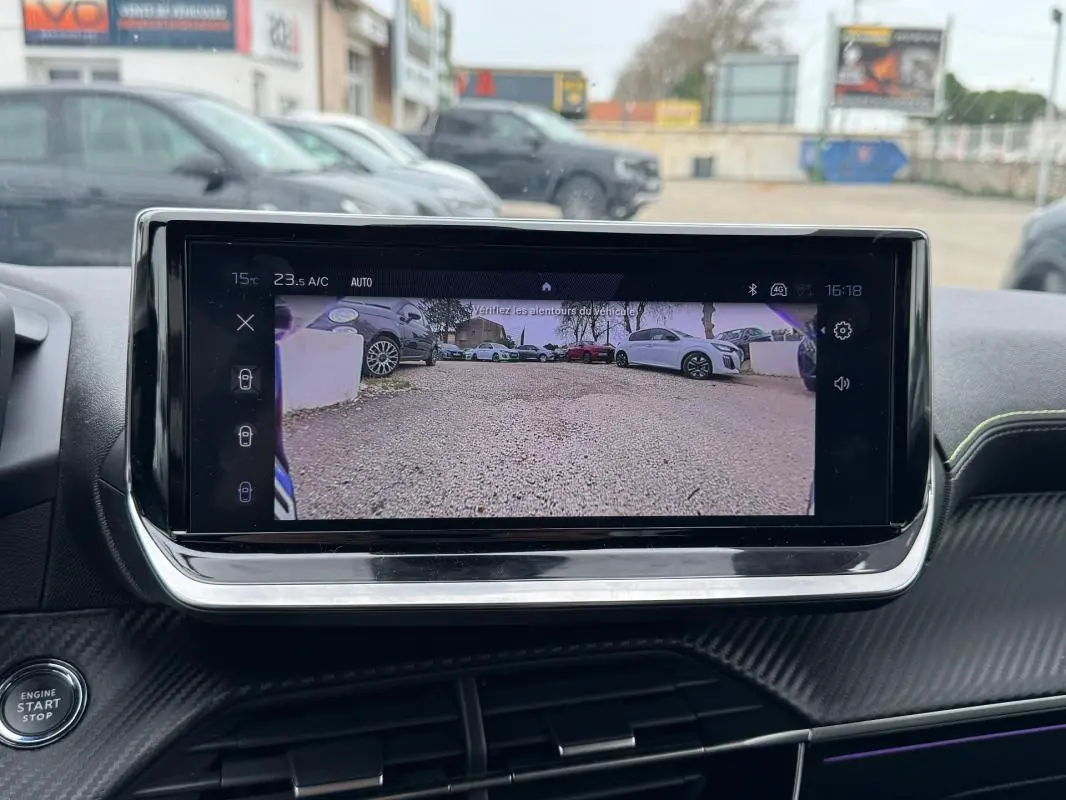 Écran tactile intérieur de la Peugeot 208 Hybrid 110 e-DCS6 GT montrant la caméra de recul, avec tableau de bord noir et détails carbone.