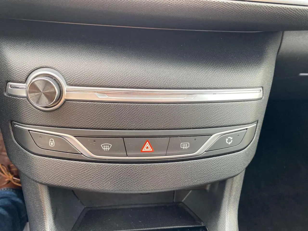 Détail du tableau de bord noir de la Peugeot 308 2018, montrant les commandes des feux de détresse et de la climatisation.
