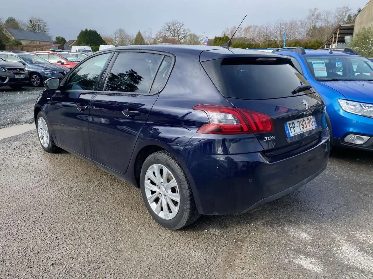 Peugeot 308 bleu foncé vue 3/4 arrière droit, avec feux arrière distinctifs et vitres teintées.
