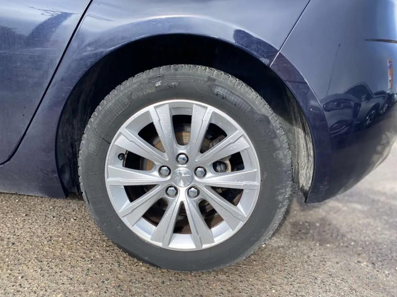 Gros plan sur la roue arrière droite d'une Peugeot 308 2018 bleu foncé avec jante argentée et pneus pluie.