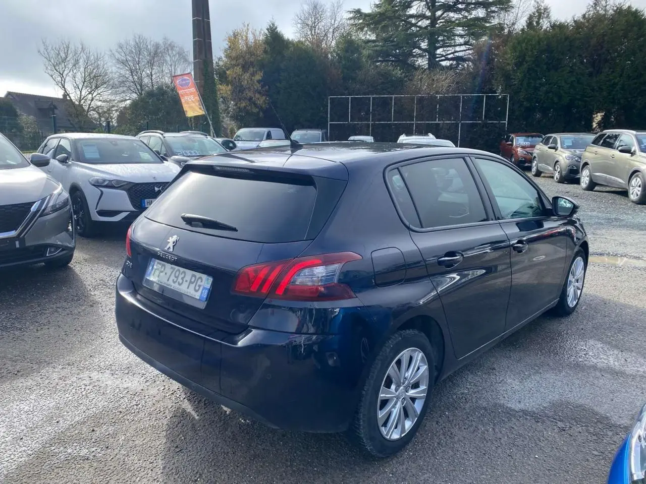 Peugeot 308 bleu foncé vue 3/4 arrière droit, avec feux arrière distinctifs et vitres teintées.