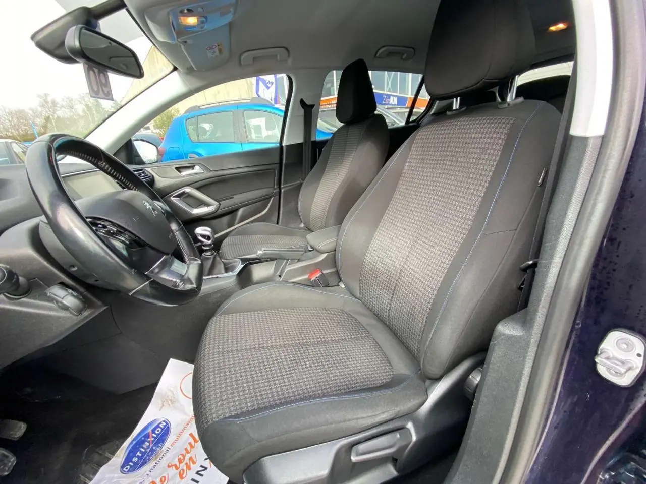 Vue intérieure côté conducteur de la Peugeot 308 2018 bleu foncé, montrant les sièges avant et le volant avec boîte manuelle.