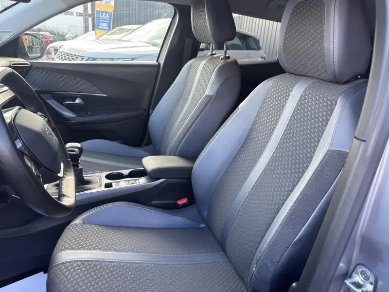 Vue intérieure côté conducteur du Peugeot 2008 2020, sièges tissu tri-matière gris avec surpiqûres bleues et console centrale.