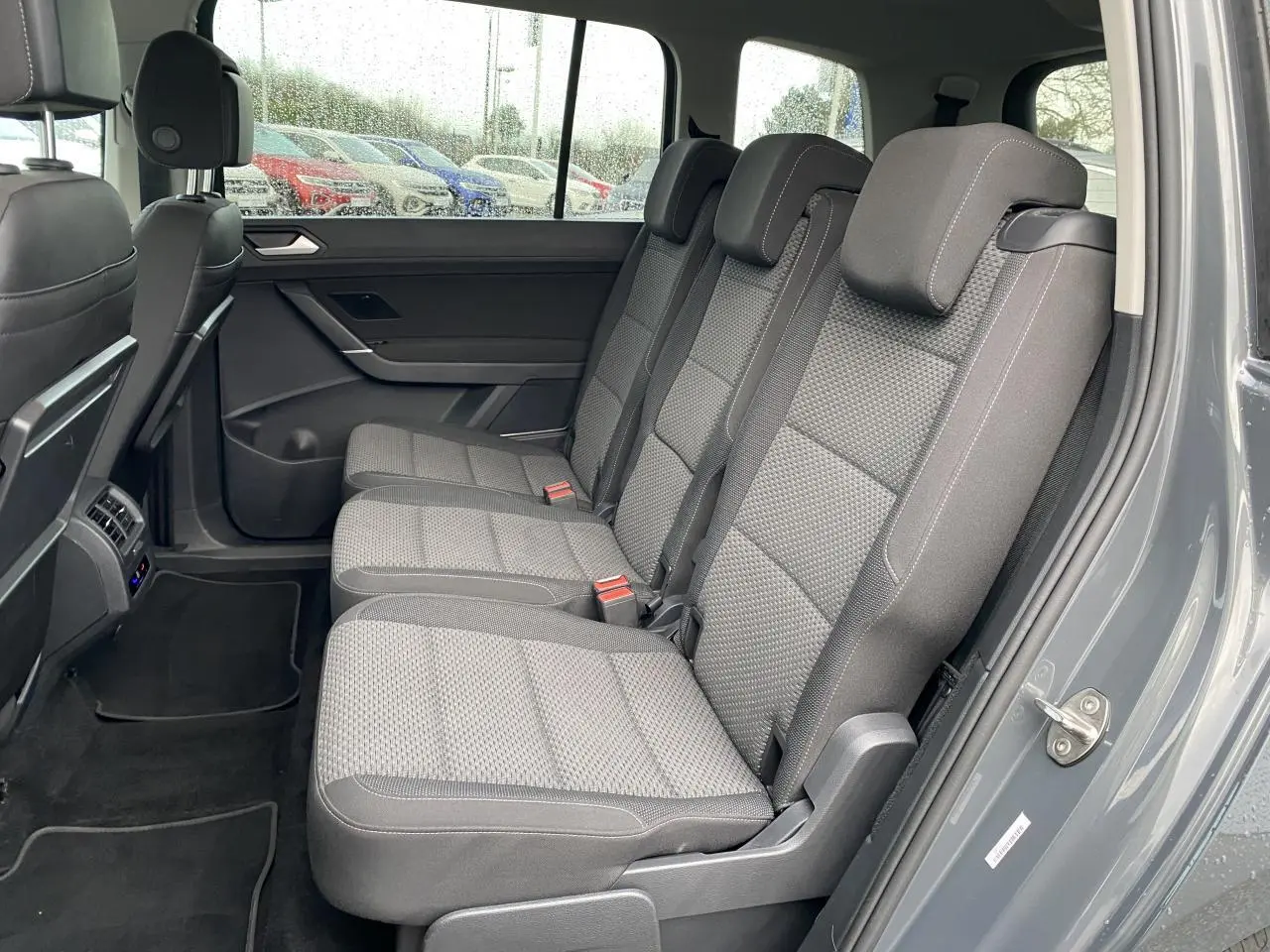 Vue intérieure côté droit sur les sièges arrière gris tissu du Volkswagen Touran gris Dauphin 2025.