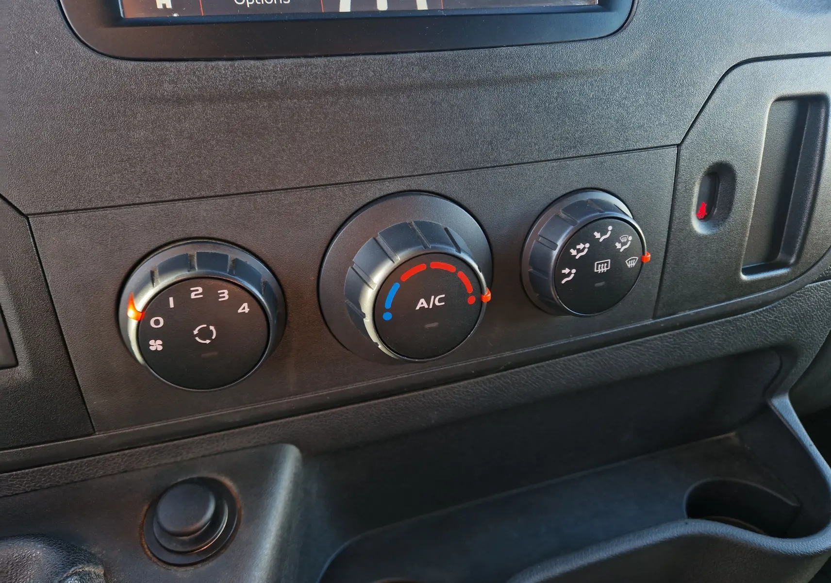 Gros plan sur les commandes de climatisation du tableau de bord du Renault Master blanc, avec réglages manuels et écran partiel en haut.