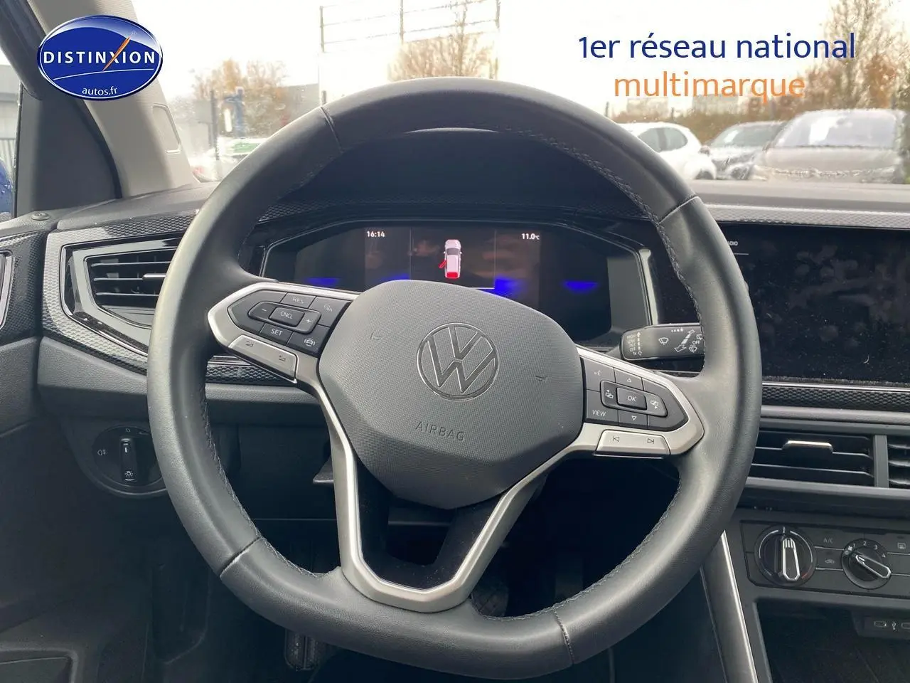 Vue intérieure centrée sur le volant cuir multifonction de la Volkswagen Polo 2025, avec tableau de bord digital en arrière-plan.