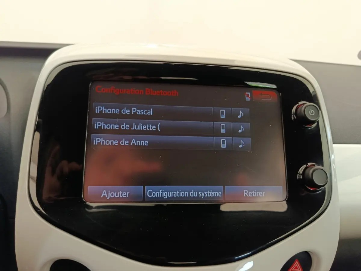 Écran tactile central de la Toyota Aygo blanc, affichant la configuration Bluetooth avec plusieurs iPhones connectés.