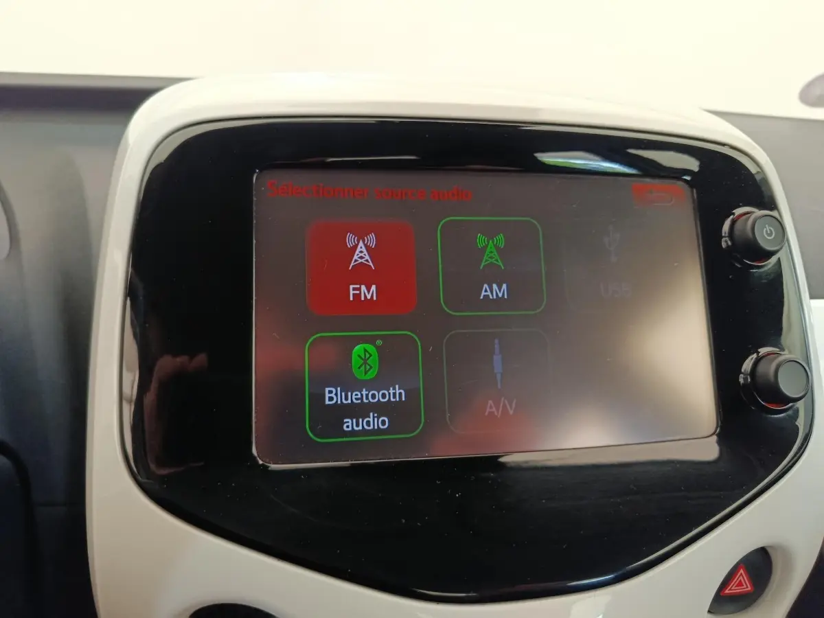 Écran tactile central de la Toyota Aygo blanche, affichant les options audio FM, AM et Bluetooth.