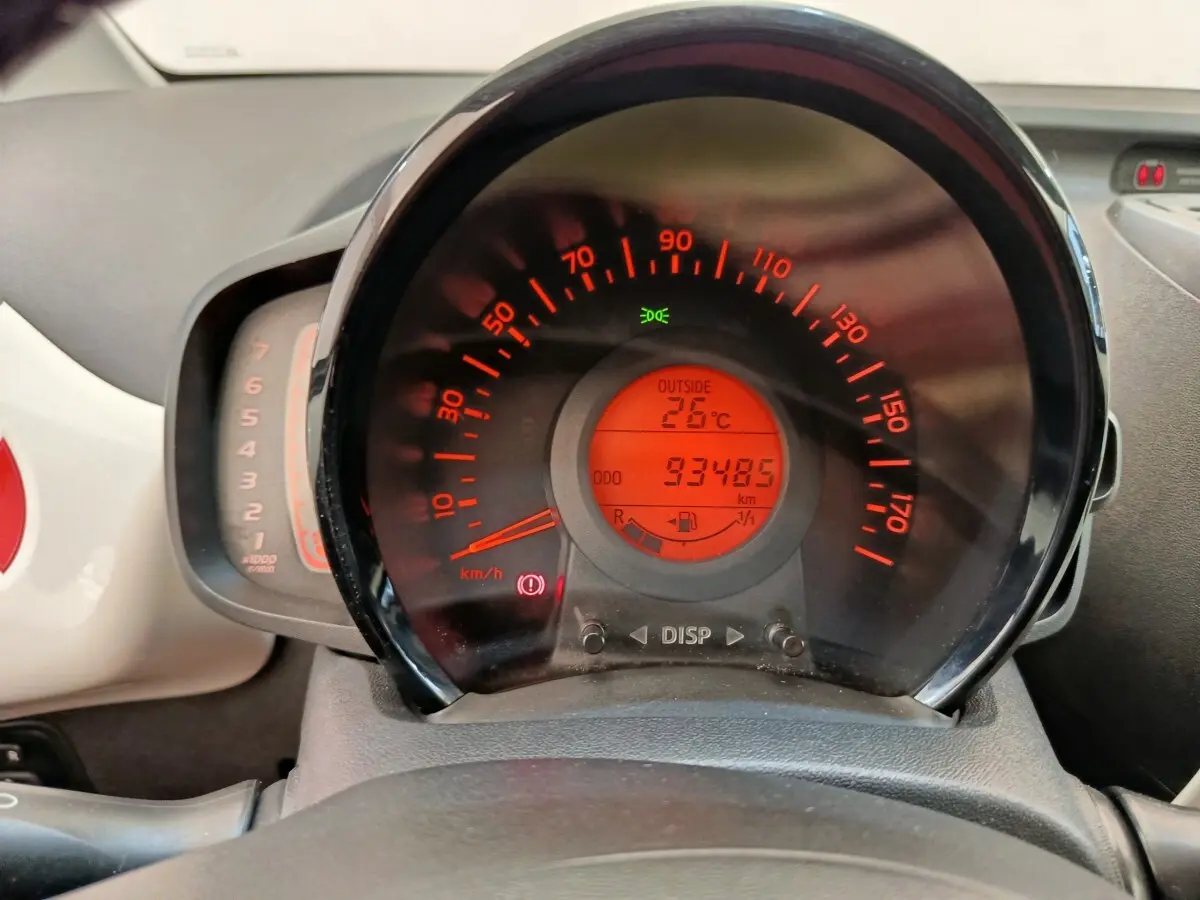 Vue rapprochée du tableau de bord de la Toyota Aygo blanc, affichant le compteur de vitesse et la température extérieure à 26°C.