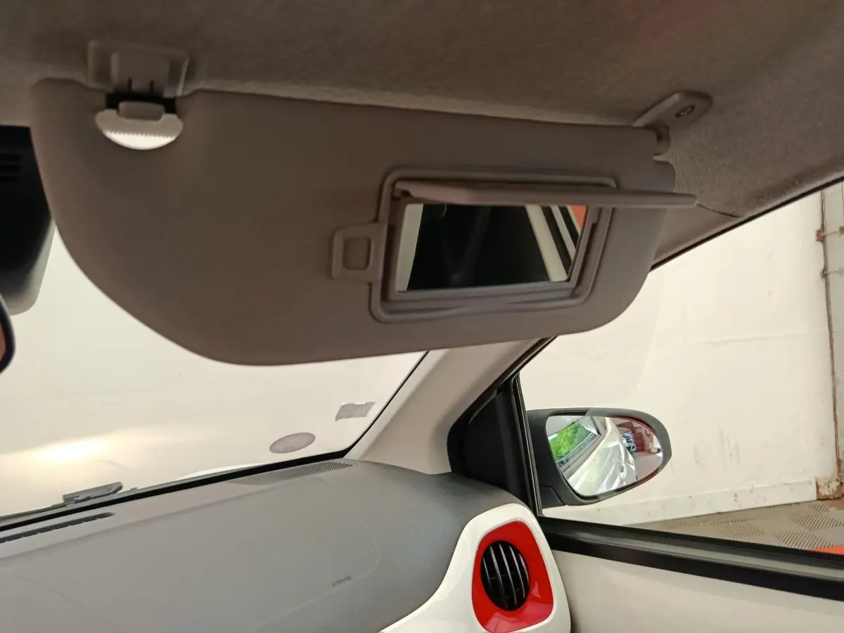Intérieur de la Toyota Aygo blanc vue côté passager, avec pare-soleil baissé et miroir de courtoisie ouvert.