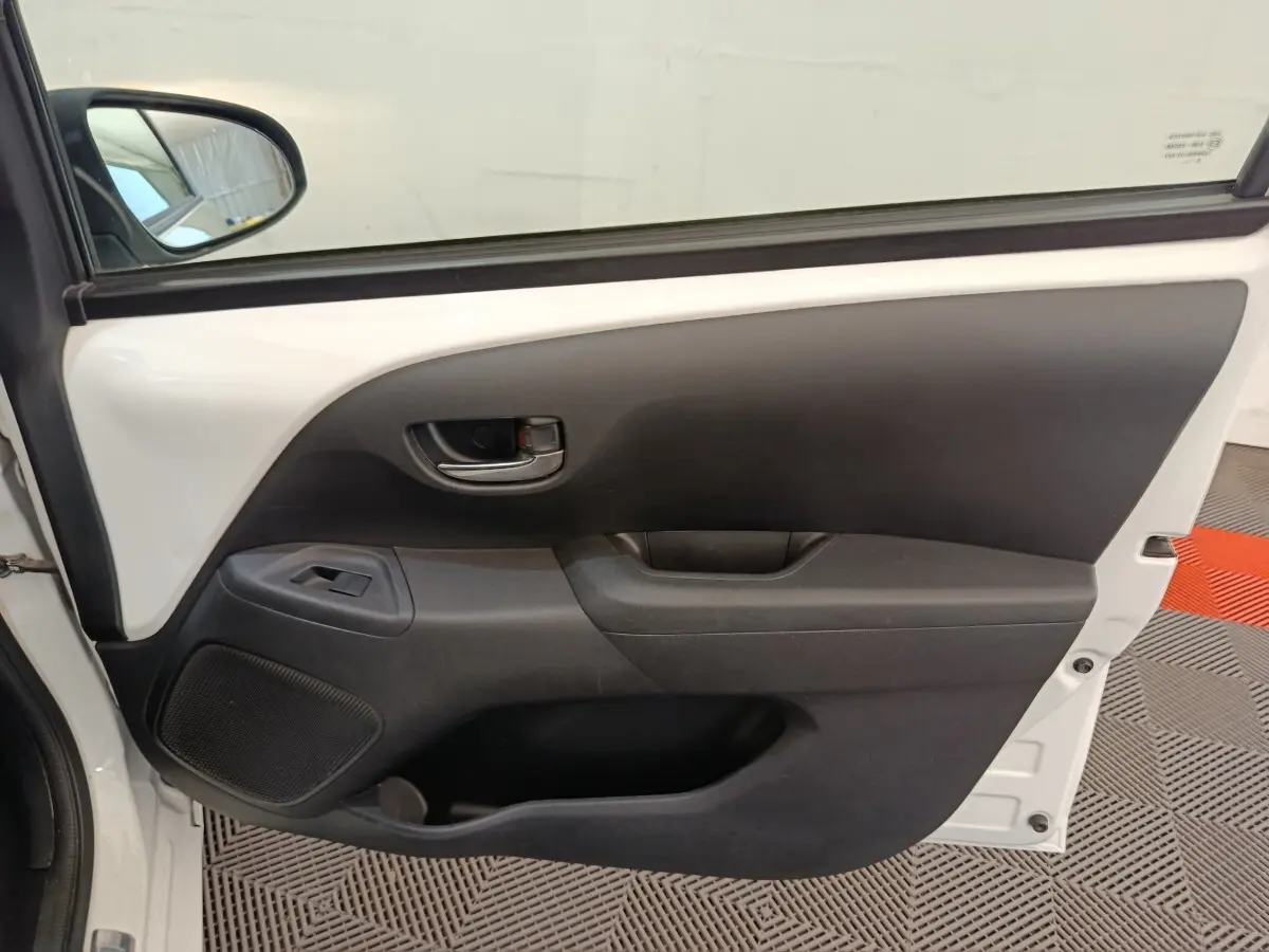 Vue rapprochée de la porte avant gauche blanche de la Toyota Aygo 2016, avec poignée intérieure et commande de vitre.