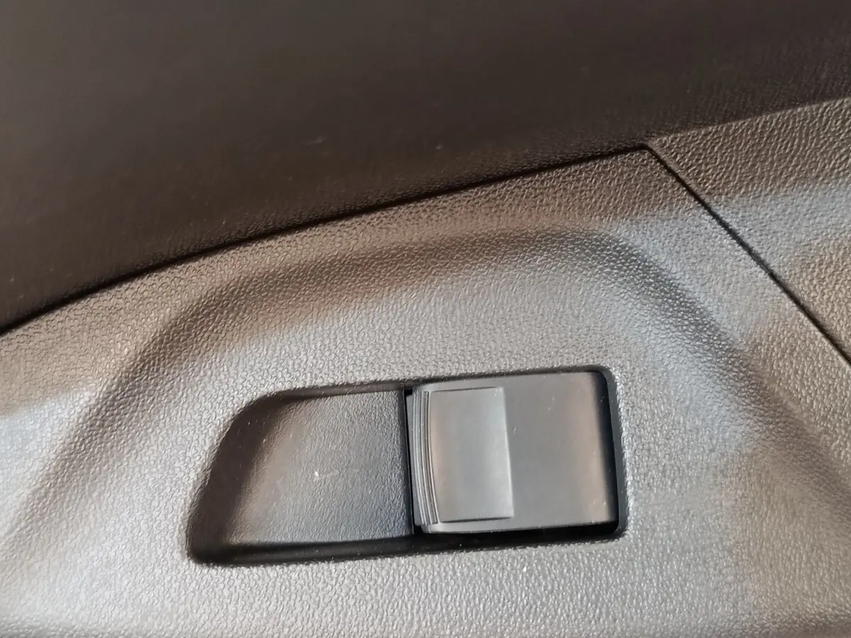 Gros plan sur l'interrupteur de réglage de siège en plastique noir dans l'habitacle d'une Toyota Aygo blanche.