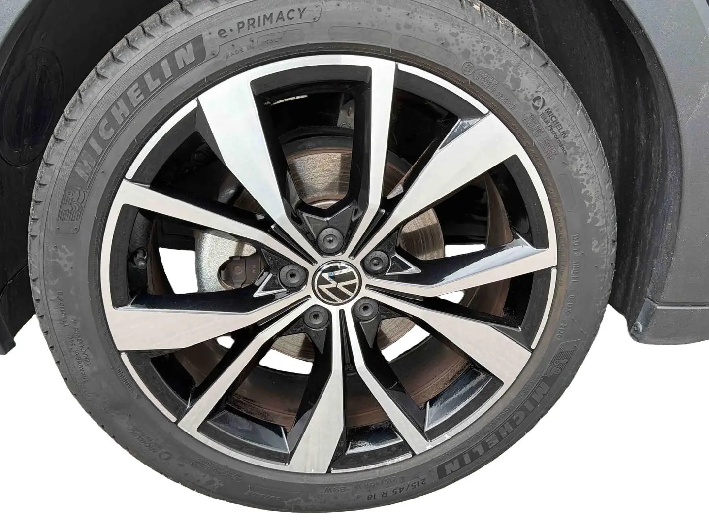 Gros plan sur la jante alliage 18 pouces bicolore noir et argent du Volkswagen T-Cross gris, avec pneu Michelin visible.