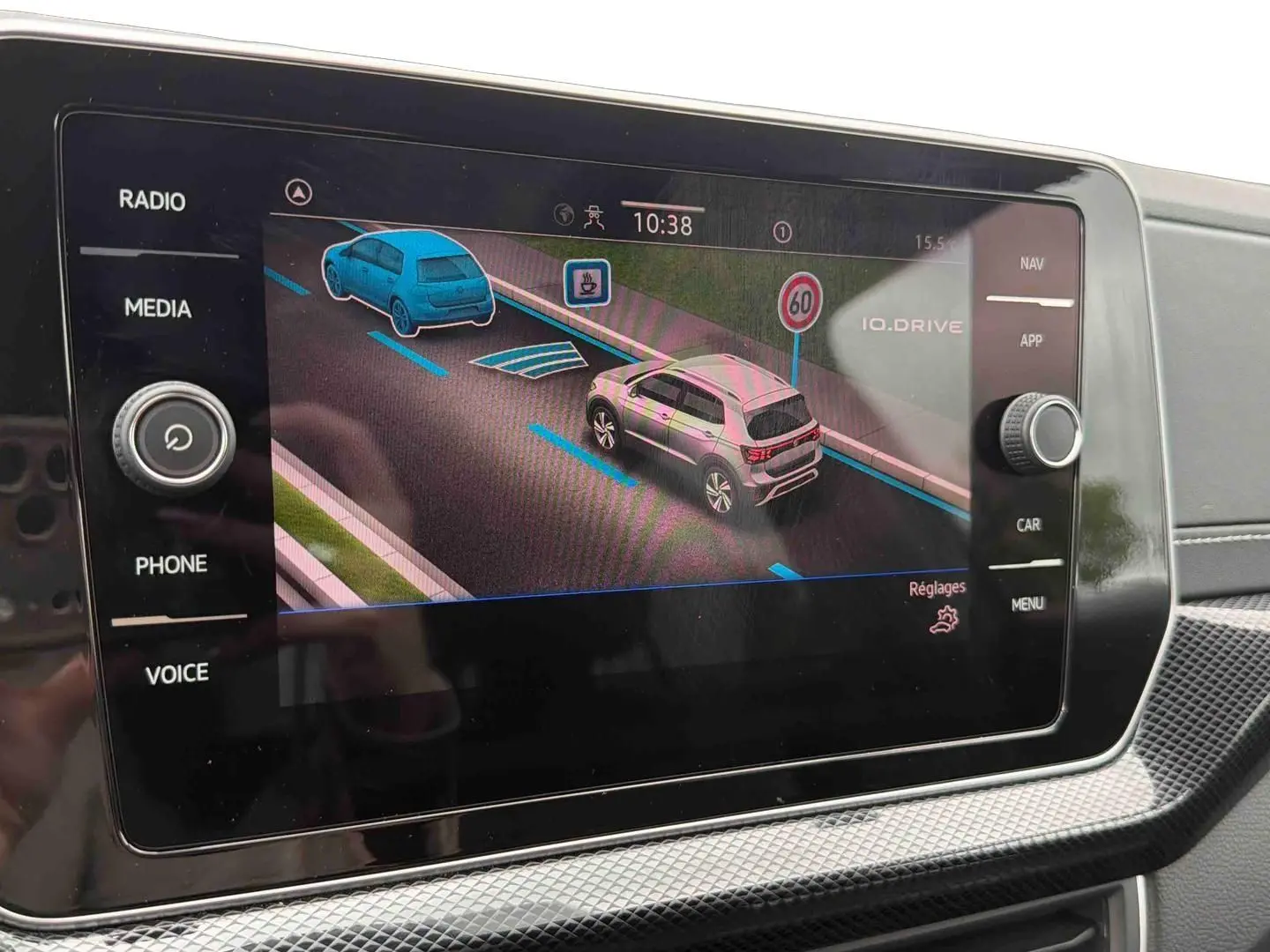Écran tactile intérieur montrant l'aide au stationnement avec vue 3/4 arrière du Volkswagen T-Cross gris.
