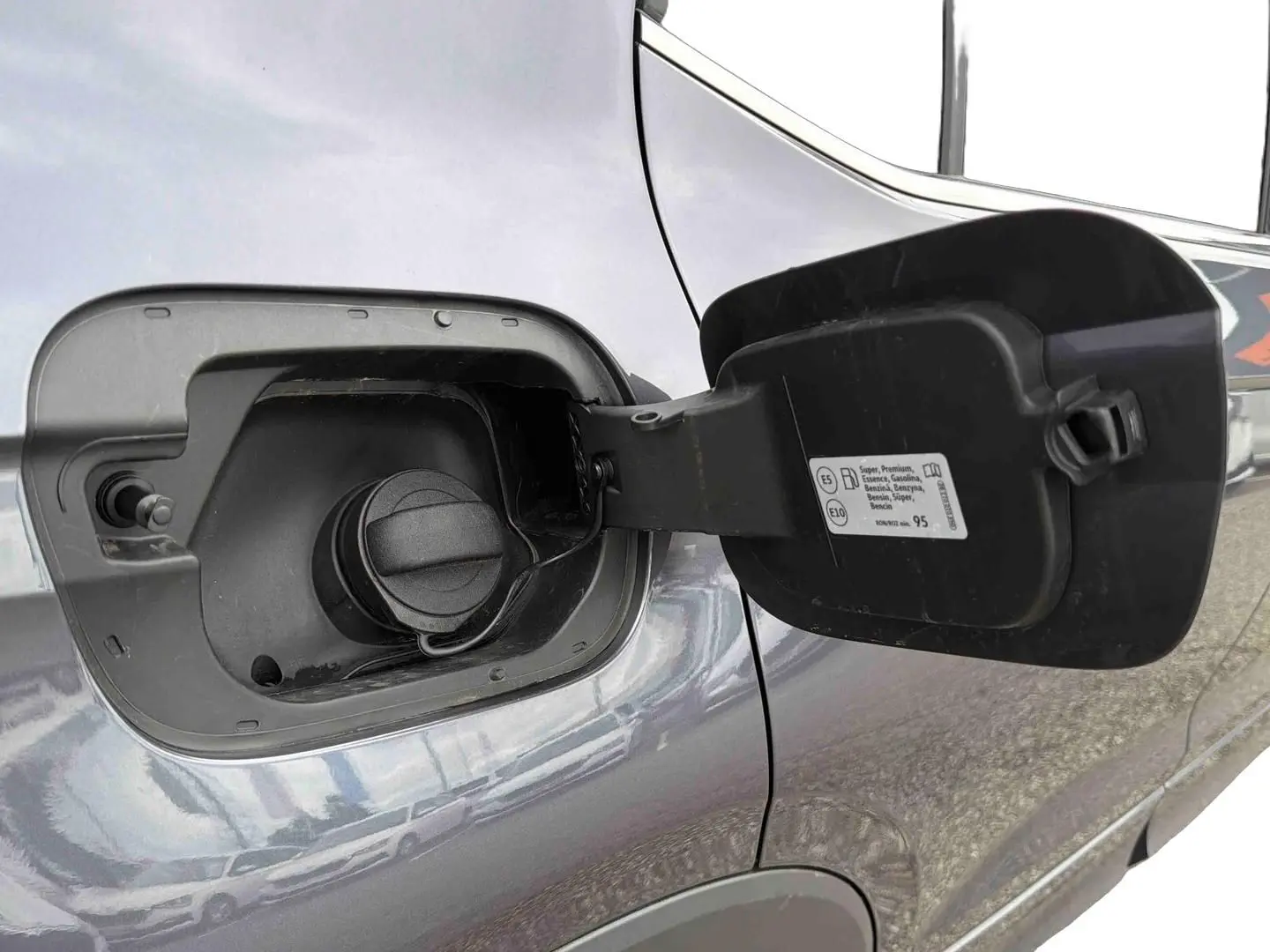 Gros plan sur la trappe à carburant ouverte côté gauche d’un Volkswagen T-Cross gris 2025.