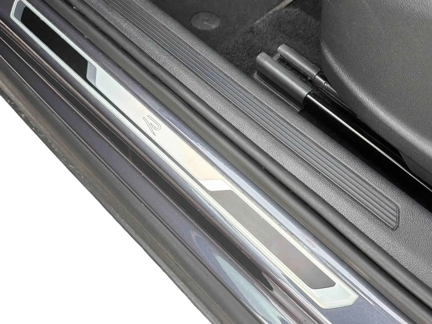 Gros plan sur la plaque de seuil de porte côté conducteur du Volkswagen T-Cross gris, avec logo R visible.