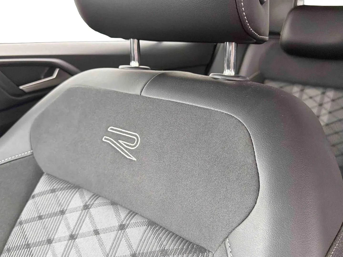 Gros plan sur l'appui-tête avant gris foncé du Volkswagen T-Cross avec logo R brodé, intérieur tissu et cuir.