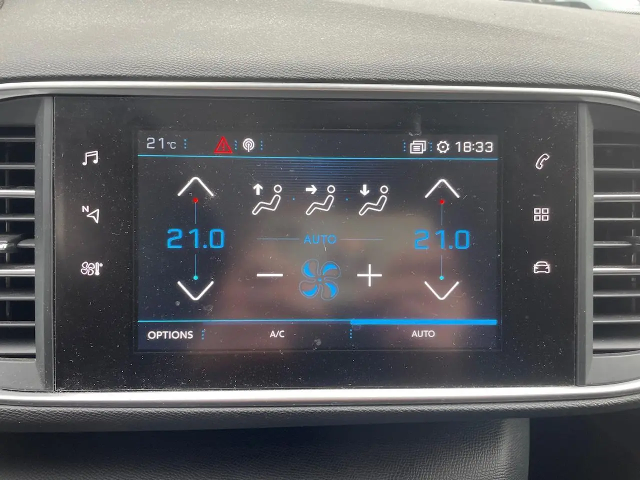 Écran tactile central de la Peugeot 308 gris Hurricane montrant la climatisation réglée à 21°C en mode automatique
