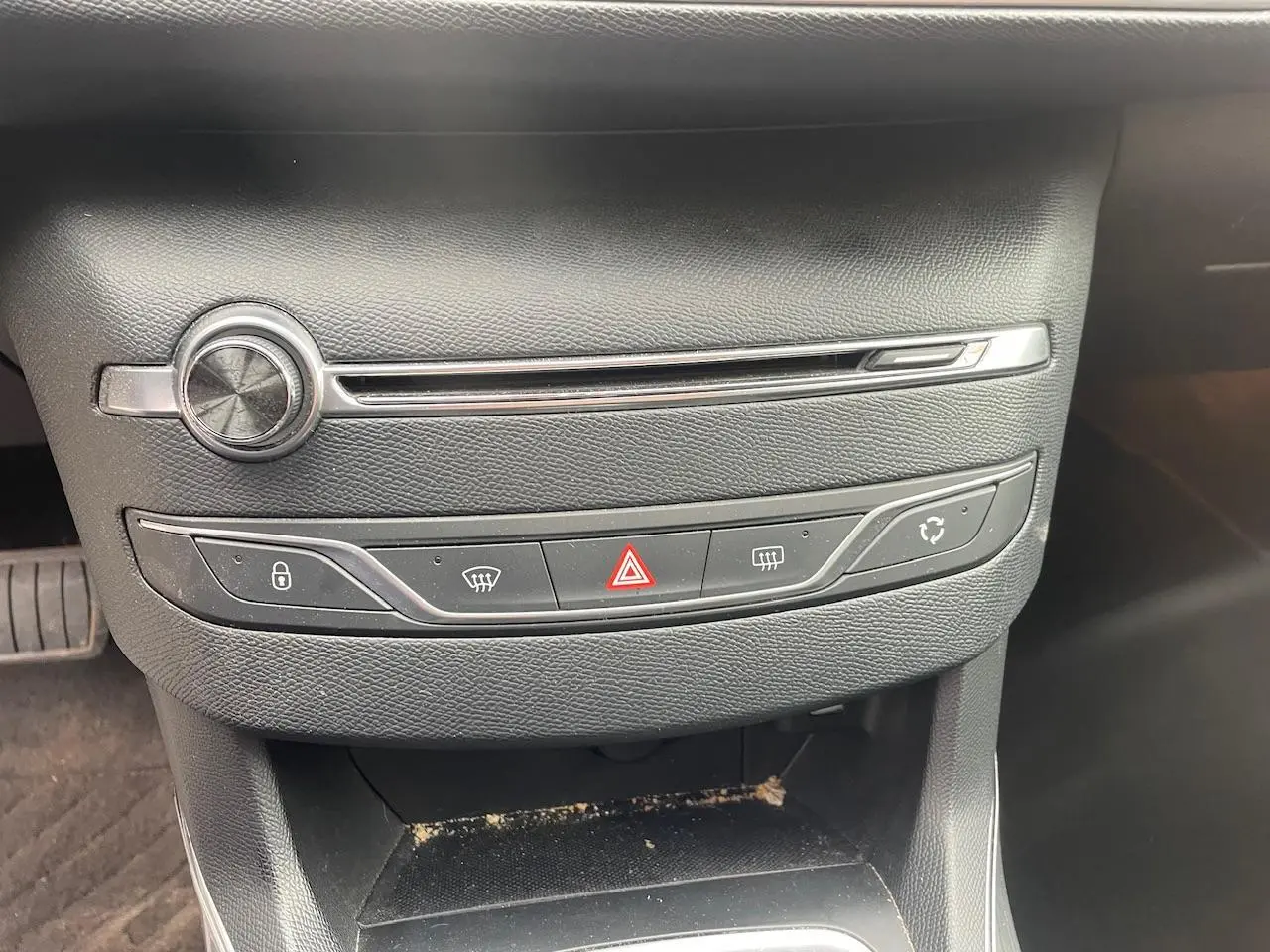 Gros plan sur la console centrale noire de la Peugeot 308 gris Hurricane, avec commandes de climatisation et bouton hazard.