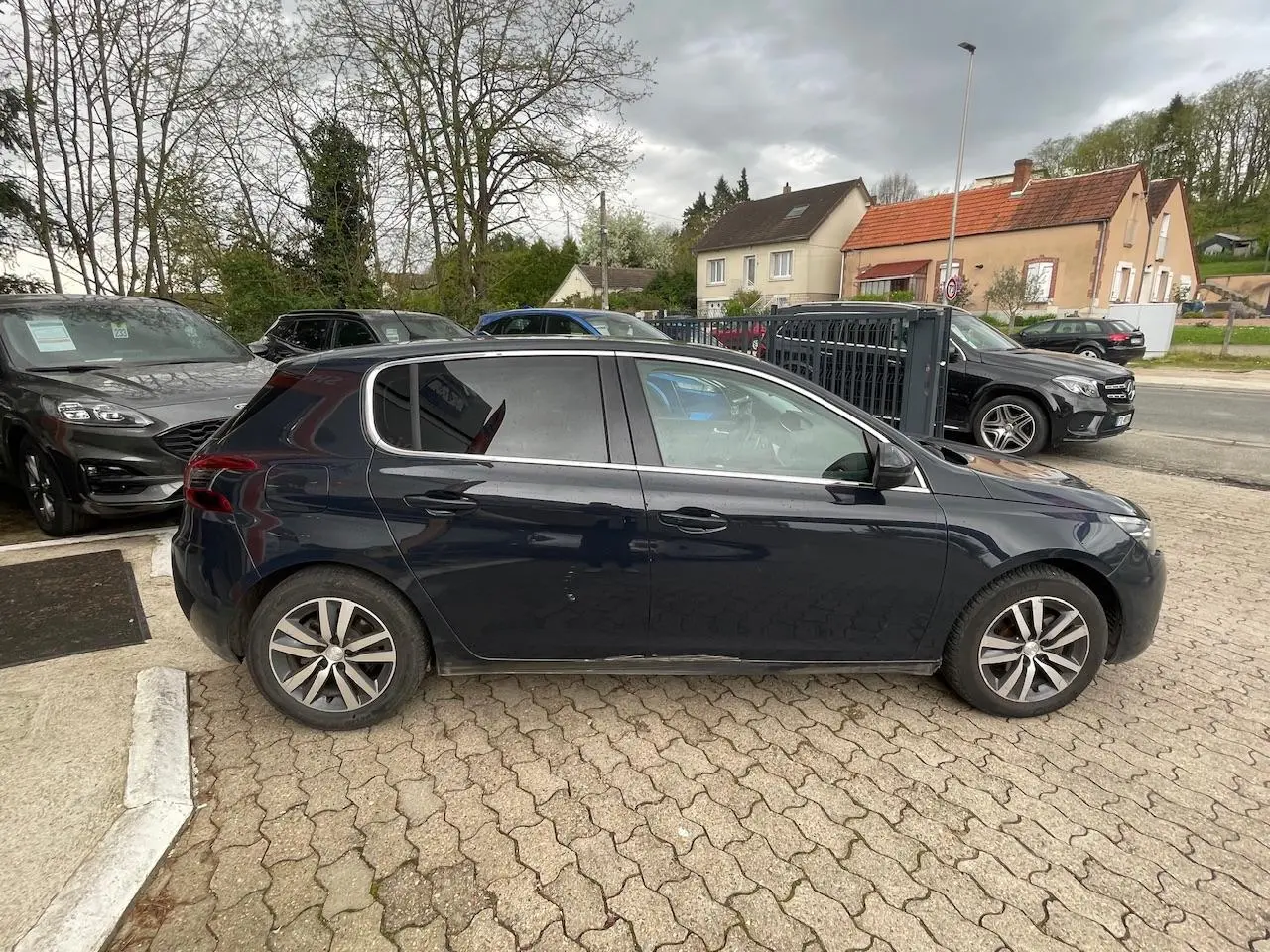 Peugeot 308 gris hurricane vue de profil côté gauche, avec vitres surteintées et jantes alliage.