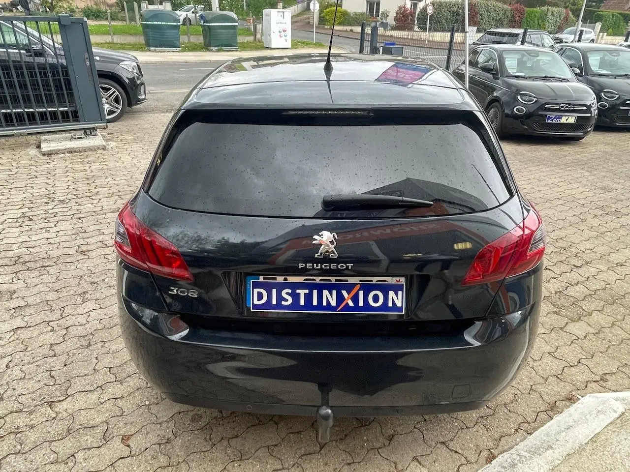 Vue arrière d'une Peugeot 308 gris foncé avec vitres surteintées et logo distinctif sur le hayon.