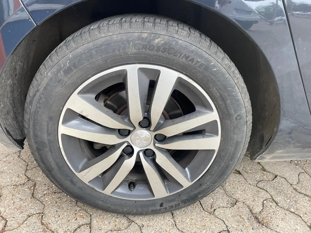 Gros plan sur la roue avant gauche d'une Peugeot 308 gris Hurricane avec jante alliage à huit branches.