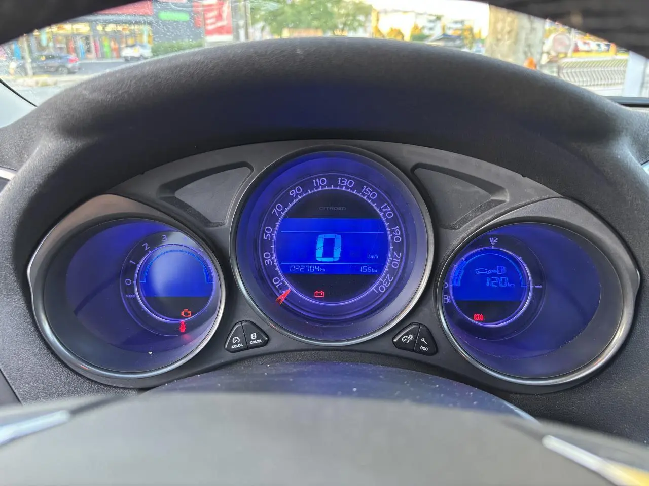 Tableau de bord numérique bleu de la Citroën C4 2012, affichant la vitesse et compte-tours au centre du volant.