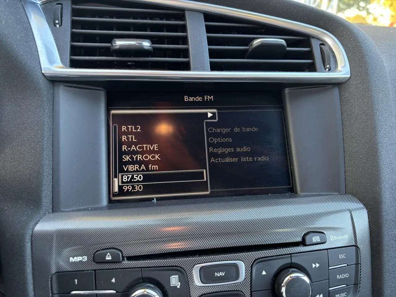 Gros plan sur l'écran de navigation eMyWay et la console centrale de la Citroën C4 gris clair de 2012.