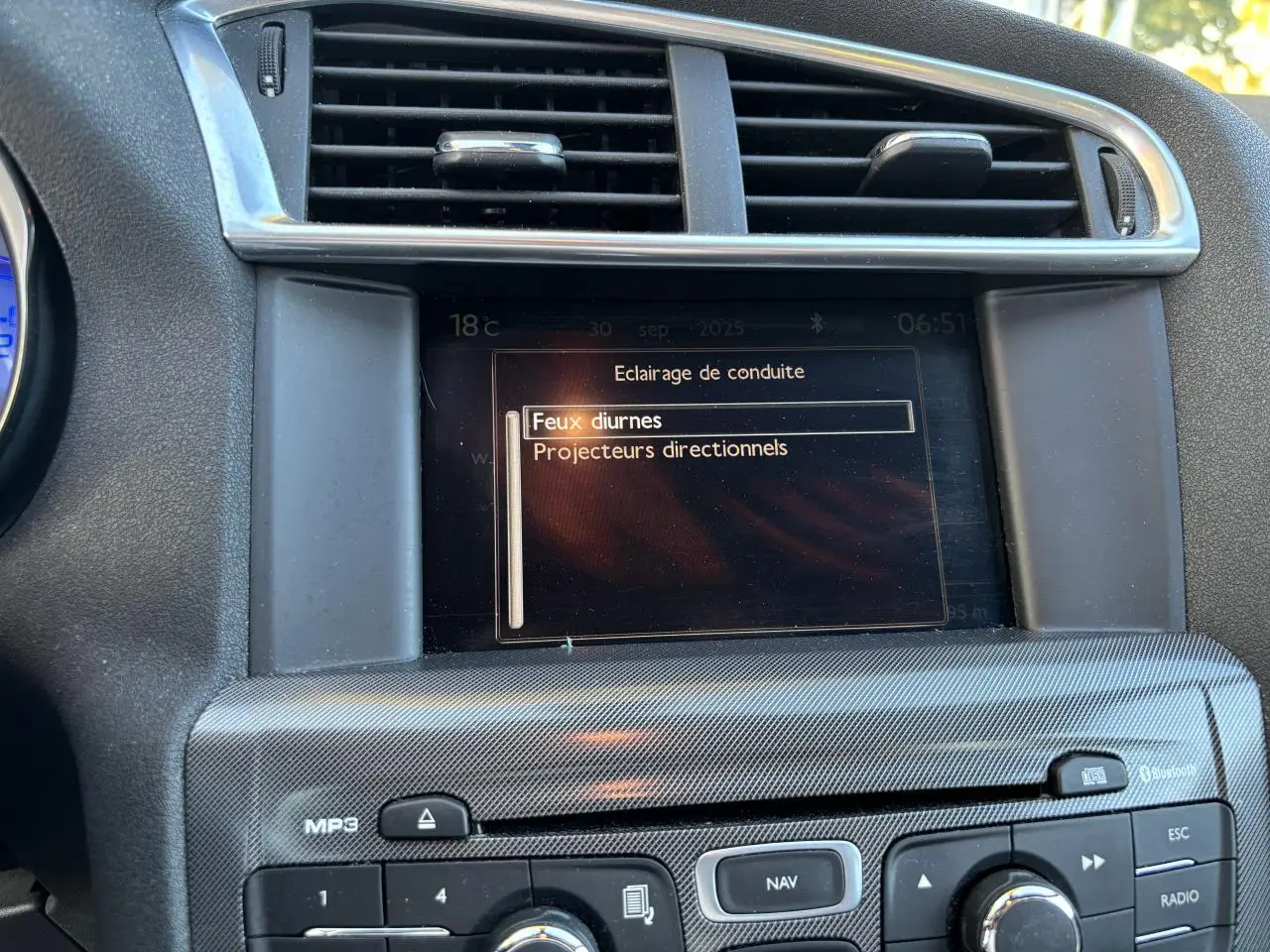 Écran central de la Citroën C4 2012 montrant le menu d'éclairage, entouré de commandes et grilles d'aération.