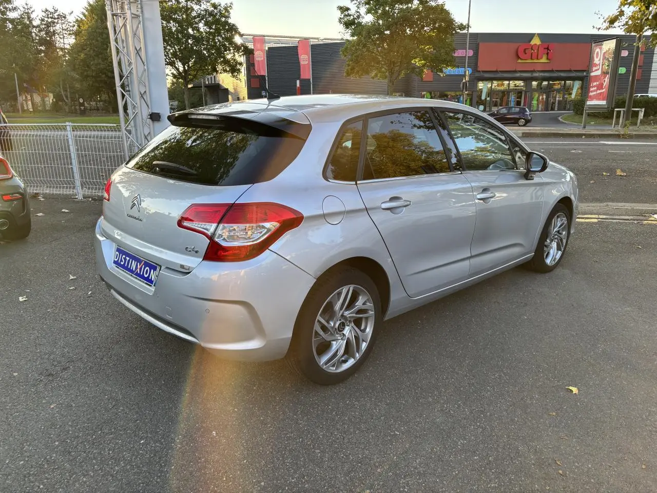 Vue 3/4 arrière droite d'une Citroën C4 gris clair avec vitres arrière surteintées et jantes alliage.