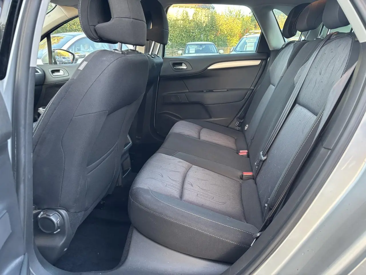 Vue intérieure côté droit des sièges arrière en tissu gris foncé d'une Citroën C4 gris clair de 2012.