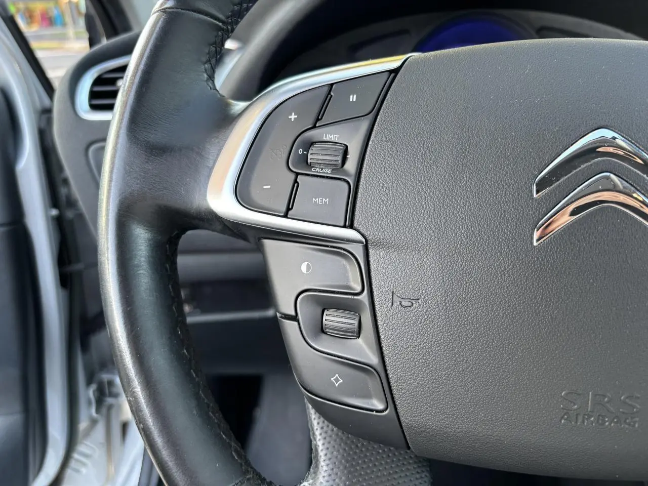 Gros plan sur le volant noir de la Citroën C4 gris clair, montrant les commandes de régulateur et limiteur de vitesse.