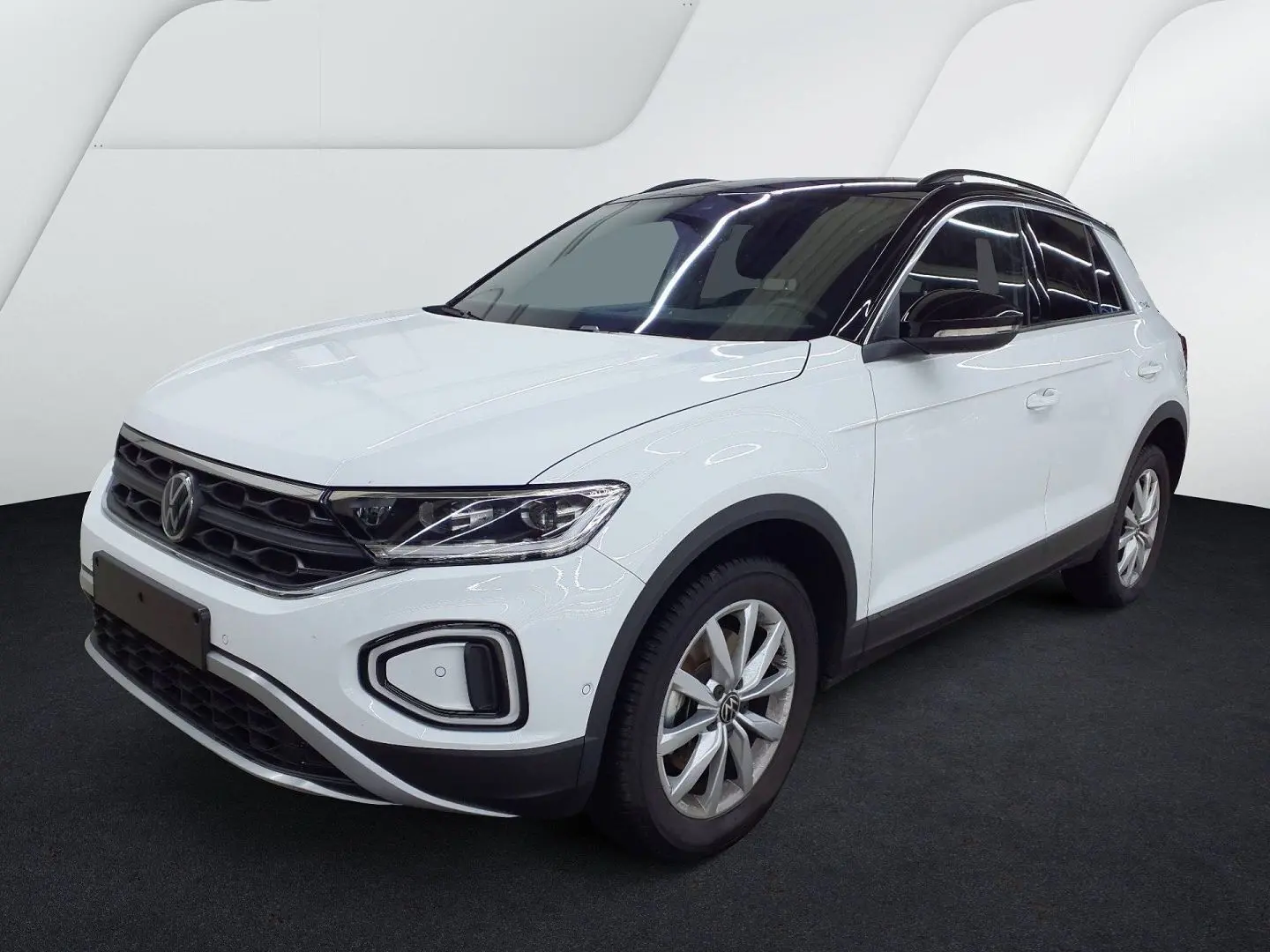 Volkswagen T-Roc blanc pure avec toit noir, vue 3/4 avant droit, jantes alliage et calandre noire.
